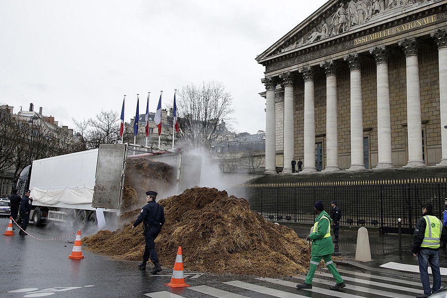 French police an municipal workers walk near a large pile of manure sits in front of the National Assembly in Paris